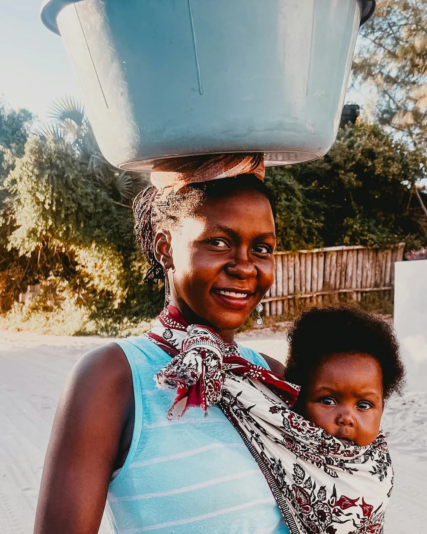 Mama akitabasamu akiwa amembeba mtoto mgongoni