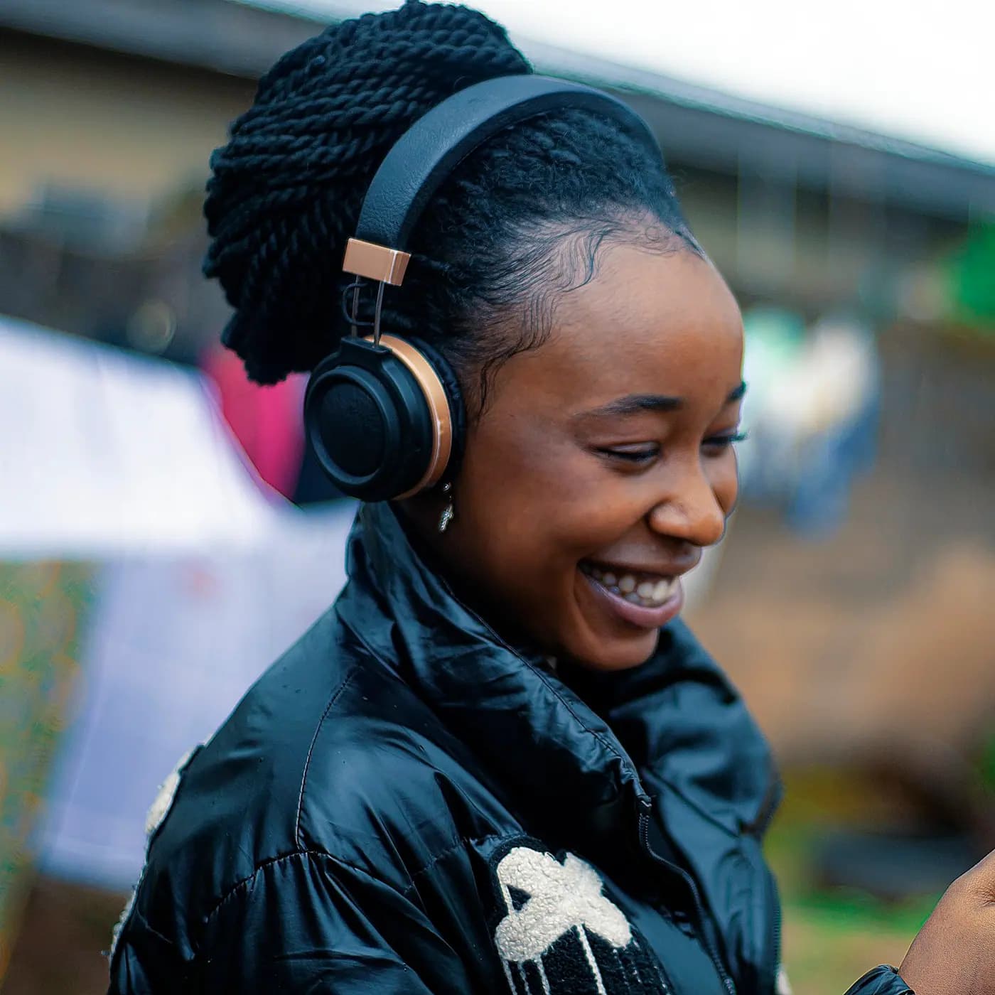 Msichana mwenye headphones akitabasamu akiangalia simu yake